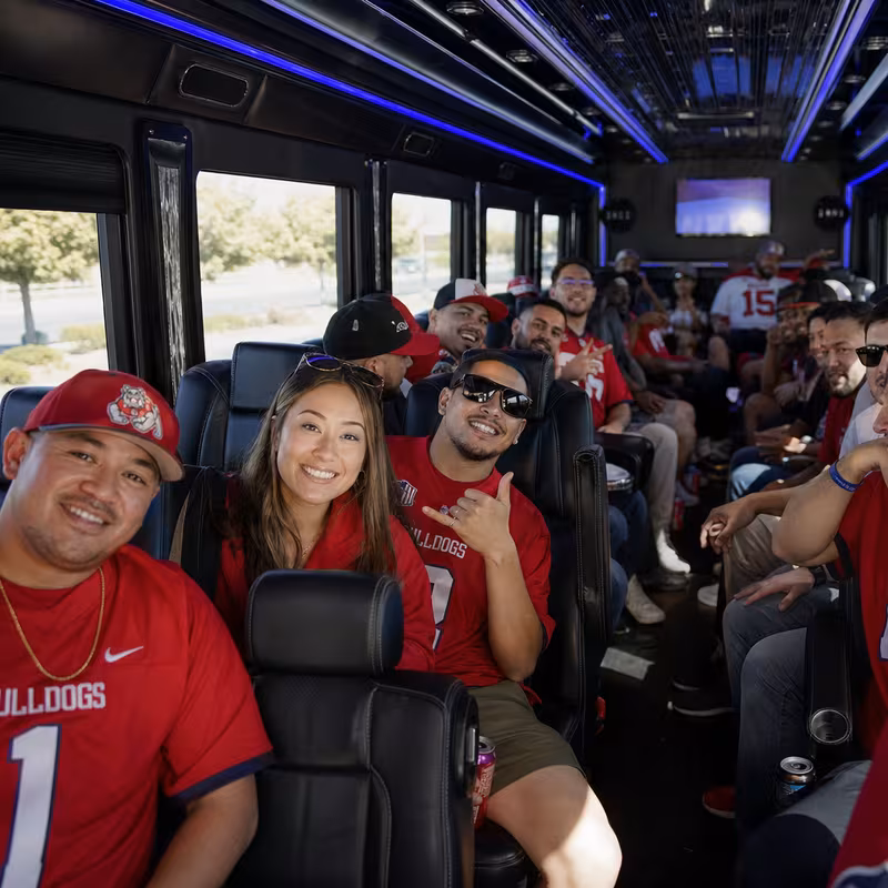Group boarding a white charter bus for Sporting Event Transportation transportation in Fresno
